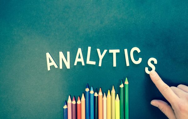 Analytics written in plastic letters above multi-coloured pencils